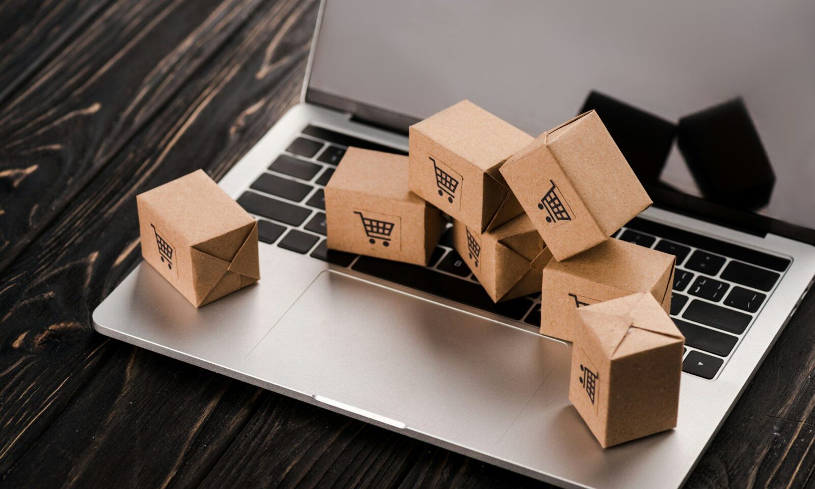 small-carton-boxes-on-laptop-with-blank-screen-e-commerce-concept