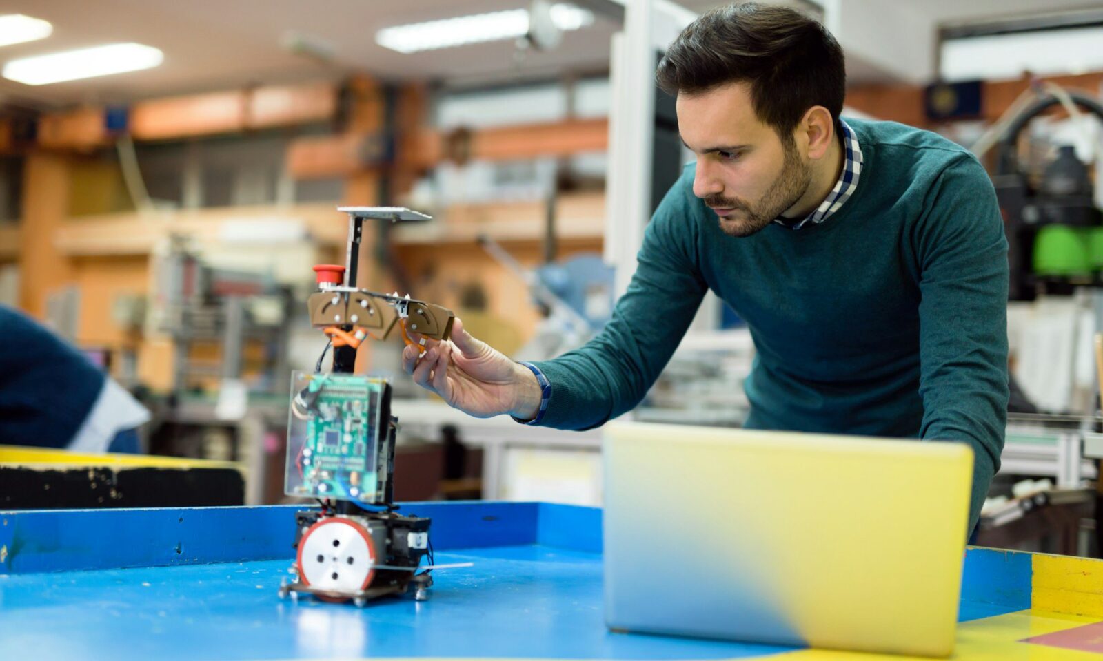 young-engineer-testing-his-robot-in-workshop